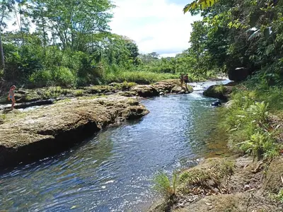 a river with some people standing on the rocks at Villa Ceiba in Fortuna