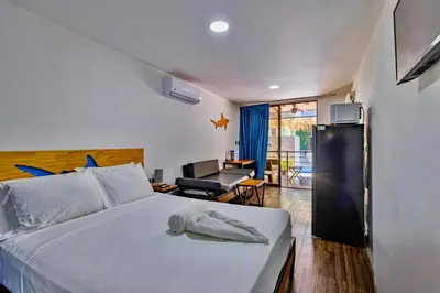 a bedroom with a bed and a living room at Shark Town Mal Pais in Santa Teresa Beach
