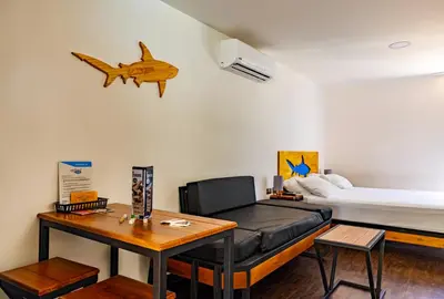 a living room with a black leather couch and a bed at Shark Town Mal Pais in Santa Teresa Beach
