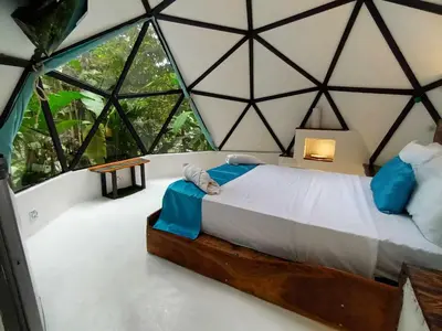 a bed in a room with a large window at Glamping Tomaselli in Manuel Antonio