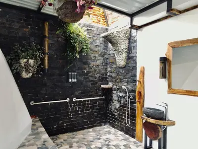 a bathroom with a black brick wall at Glamping Tomaselli in Manuel Antonio