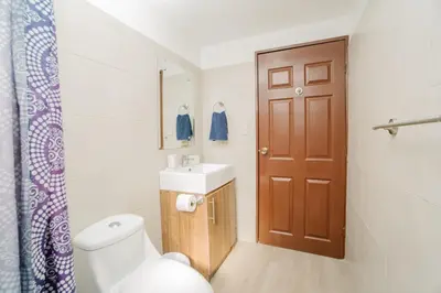 a bathroom with a toilet and a sink and a door at Apartamento Ganesha Liberia in Santa Ana