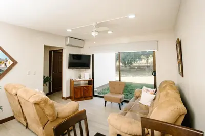 a living room with a couch and chairs and a tv at Apartamento Ganesha Liberia in Santa Ana
