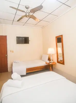 a bedroom with two beds and a ceiling fan at Hotel Aldea Chorotega Puntarenas in Puntarenas