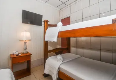 a bedroom with two bunk beds and a television at Hotel Aldea Chorotega Puntarenas in Puntarenas