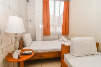 a small room with two beds and a table with a lamp at Hotel Aldea Chorotega Puntarenas in Puntarenas