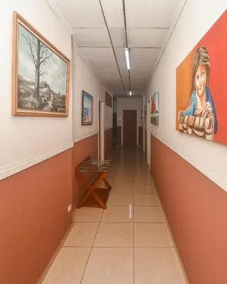 a hallway in a hospital with paintings on the walls at Hotel Aldea Chorotega Puntarenas in Puntarenas