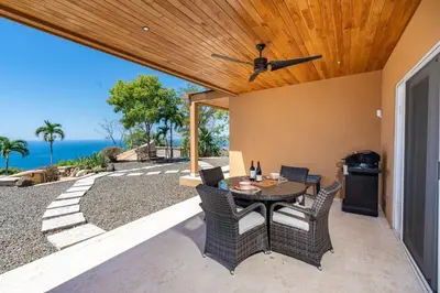 a patio with a table and chairs and the ocean at Stunning Mountaintop Property with Stylish Main Home, Private Guesthouse & Infinity Pool in Santa Cruz