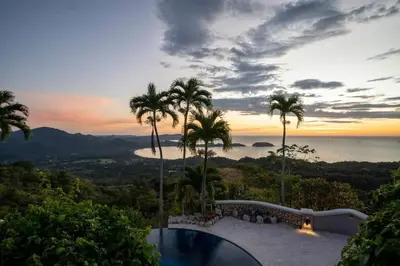 a villa with a view of the ocean and palm trees at Stunning Mountaintop Property with Stylish Main Home, Private Guesthouse & Infinity Pool in Santa Cruz