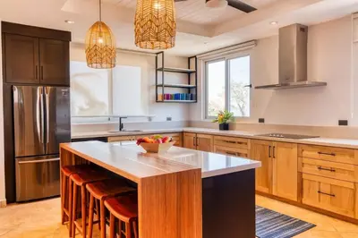 a kitchen with a large island with bar stools at Stunning Mountaintop Property with Stylish Main Home, Private Guesthouse & Infinity Pool in Santa Cruz