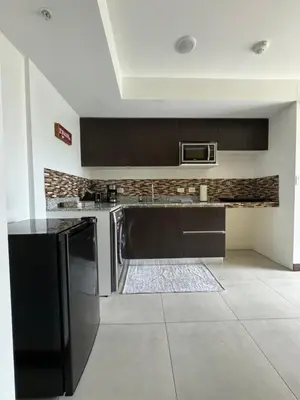 a kitchen with black cabinets and a microwave at Lovely Apartment near Costa Rica airport in Heredia