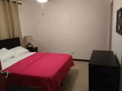 a bedroom with a bed with a red blanket at Oceanview 6th Floor Jaco Condo in Jacó