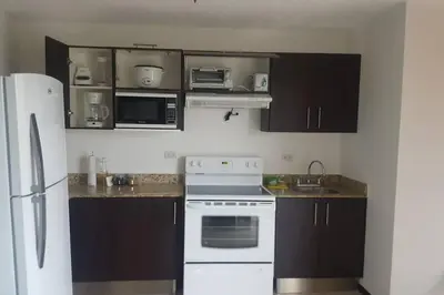 a kitchen with white appliances and brown cabinets at Oceanview 6th Floor Jaco Condo in Jacó