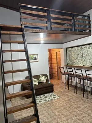a loft bed in a room with a couch and chairs at Cabaña Bambú in Cartago