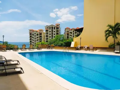 a swimming pool in a hotel with tables and chairs at Presidential Suites 4 - Spacious condo in the heart of Flamingo, sleeps 6 in Playa Flamingo