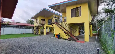 a yellow house with a staircase in front of it at Tío King Hospedaje Turístico in Uvita