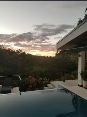 a swimming pool with a sunset in the background at New Hill top Home with a Beautiful Tropical View in Esperanza