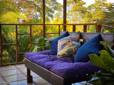 a couch with pillows sitting on a porch at Bungalows Yakari Grei in San Ramón