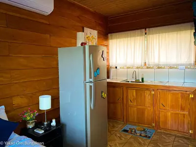 a white refrigerator in a kitchen with wooden cabinets at Bungalows Yakari Grei in San Ramón