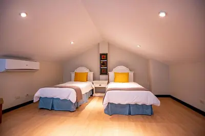 a attic room with two beds with yellow pillows at Adults Only 4BR Penthouse w Partial Ocean View, Carao Reserva Conchal in Playa Conchal