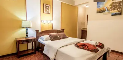 a bedroom with two beds and a table with a lamp at Hotel Amón Real Costa Rica in San José