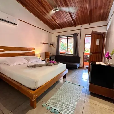a bedroom with a bed and a couch and a television at Beach Front Bahia in Sámara