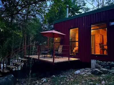 a red tiny house with a deck and an umbrella at Hotel de Montaña El Pelicano in San Isidro