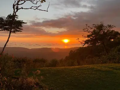 a sunset in the mountains with the sun in the sky at Refugio San Antonio - 1500 acre Private Preserve in Guaria