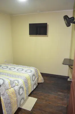 a bedroom with a bed and a tv on the wall at #3 Private room Close to Airport in Alajuela City
