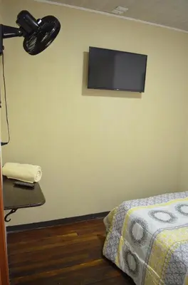 a bedroom with a television on a wall with a bed at #3 Private room Close to Airport in Alajuela City