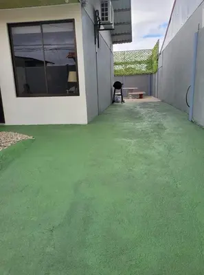 a patio with a green floor in front of a building at La casa del volcán in Fortuna