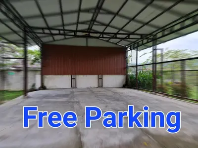 an empty parking lot with a red building at Sleep&Go! Cabina Familiar con 5 camas - Siquirres centro in Siquirres