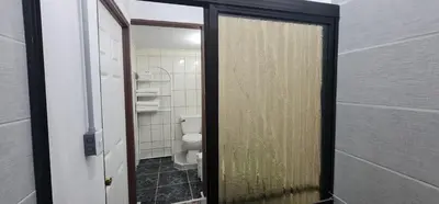 a bathroom with a toilet and a glass door at Sleep&Go! Cabina Familiar con 5 camas - Siquirres centro in Siquirres