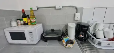 a kitchen counter with a microwave and bottles of wine at Sleep&Go! Cabina Familiar con 5 camas - Siquirres centro in Siquirres