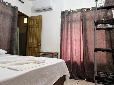 a bedroom with pink curtains and a bed and a ladder at Natural Experience House in Tortuguero