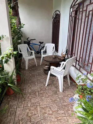 a patio with white chairs and a table and a bike at Natural Experience House in Tortuguero
