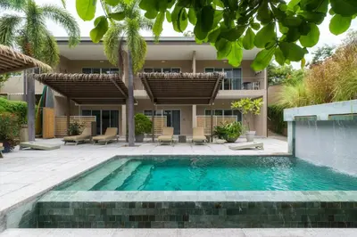 a swimming pool in front of a house at Tamarindo Bay Boutique Hotel, Apartments & Suites in Tamarindo