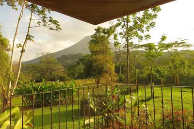 a balcony with a view of a field and mountains at Miradas Arenal Hotel & Hotsprings in Fortuna