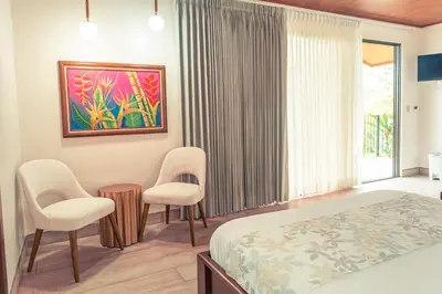 a bedroom with a bed and two chairs at Miradas Arenal Hotel & Hotsprings in Fortuna