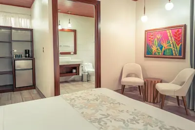 a bedroom with a bed and a bathroom with a sink at Miradas Arenal Hotel & Hotsprings in Fortuna