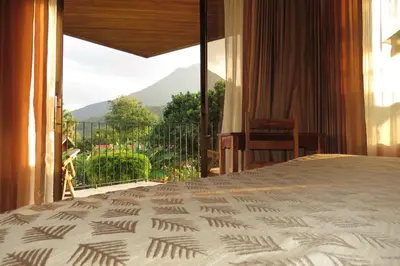 a bedroom with a bed and a balcony with a view at Miradas Arenal Hotel & Hotsprings in Fortuna