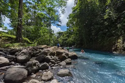 a group of people swimming in a river at Cabañas Montañas del Tenorio in San Rafael