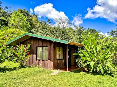 a small wooden house with a green roof at Cabañas Montañas del Tenorio in San Rafael