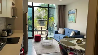 a living room with a blue couch and a table at Cozy apartment with terrace, SJ Cosmopolitan Tower #402 in San José