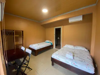 a room with two beds and a table and a desk at Hotel Ticozuma in Montezuma