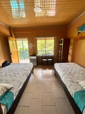 a room with two beds and a chair in it at Hotel Ticozuma in Montezuma