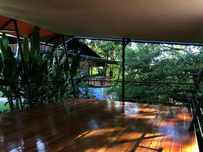 a large wooden table on a balcony with trees at Hotel Arenal Glamping in Fortuna