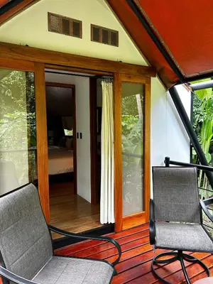 a porch with two chairs and a bed in a room at Hotel Arenal Glamping in Fortuna