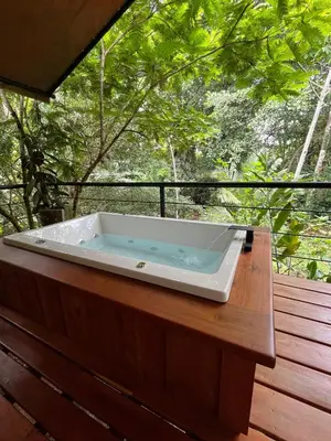 a bath tub sitting on a wooden bench on a deck at Hotel Arenal Glamping in Fortuna