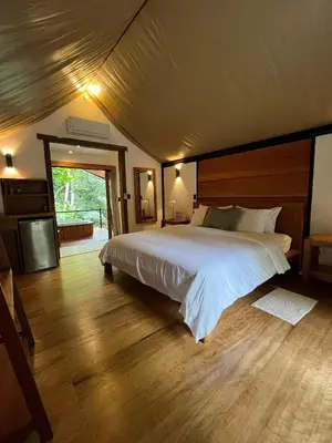 a bedroom with a large bed and a television at Hotel Arenal Glamping in Fortuna